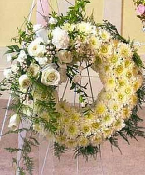 Sympathy wreath of white poms accented with white roses, ribbon and greenery.