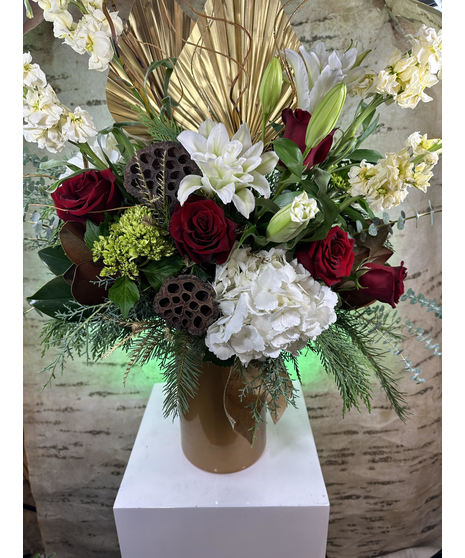 Gold geometric vase filled with seasonal red and white flowers and winter greenery