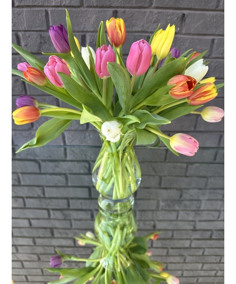 Yellow, red and purple tulips in a clear glass vase.