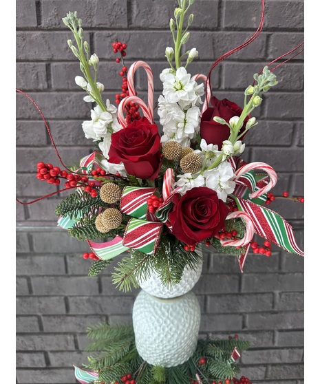 Red, white and pink flowers with winter greenery in a white cylinder vase