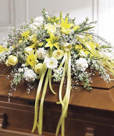 Casket spray in yellow and white flowers with green ribbons. 
