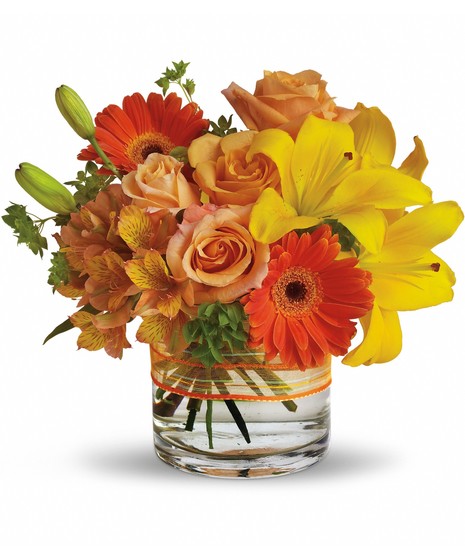 Mixed summer flowers, lilies, carnations & pompoms in a clear glass vase.
