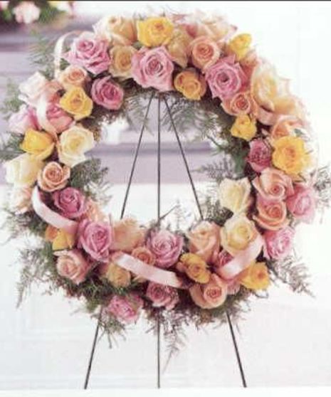 Sympathy wreath of roses in peach and pink with coordinating ribbon. 