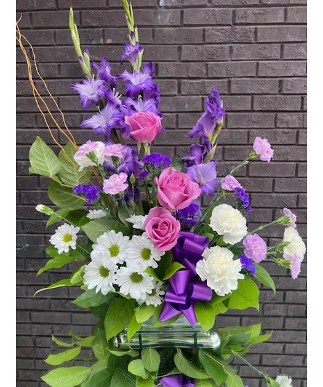 Sympathy arrangement of liatris, spider mums, larkspur, poms, carnations and greenery. 