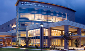 A large, multi-story building with many windows lit from within; text reads 